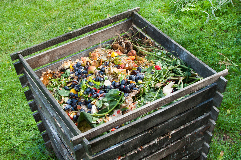 A wooden outdoor bin filled with various garden waste and organic debris, situated on a grassy area with small patches of moss, in close-up detail. The bin is constructed from dark...
<br/>
<a class=